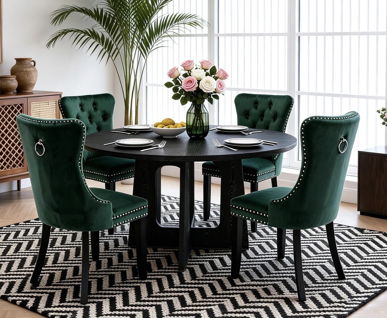 Round black dining table set with four forest green velvet chairs